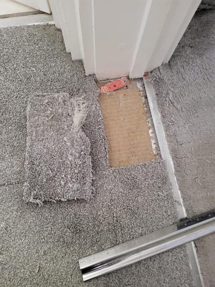 Carpet section lifted showing damage before repair