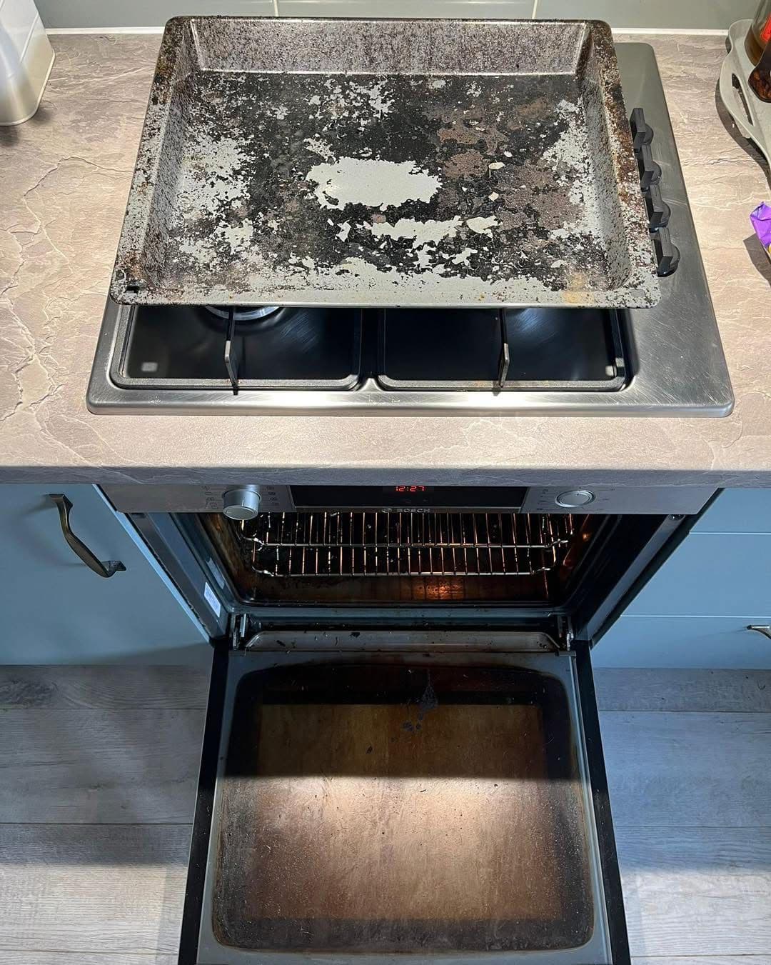 Dirty range oven with soiled baking tray before cleaning
