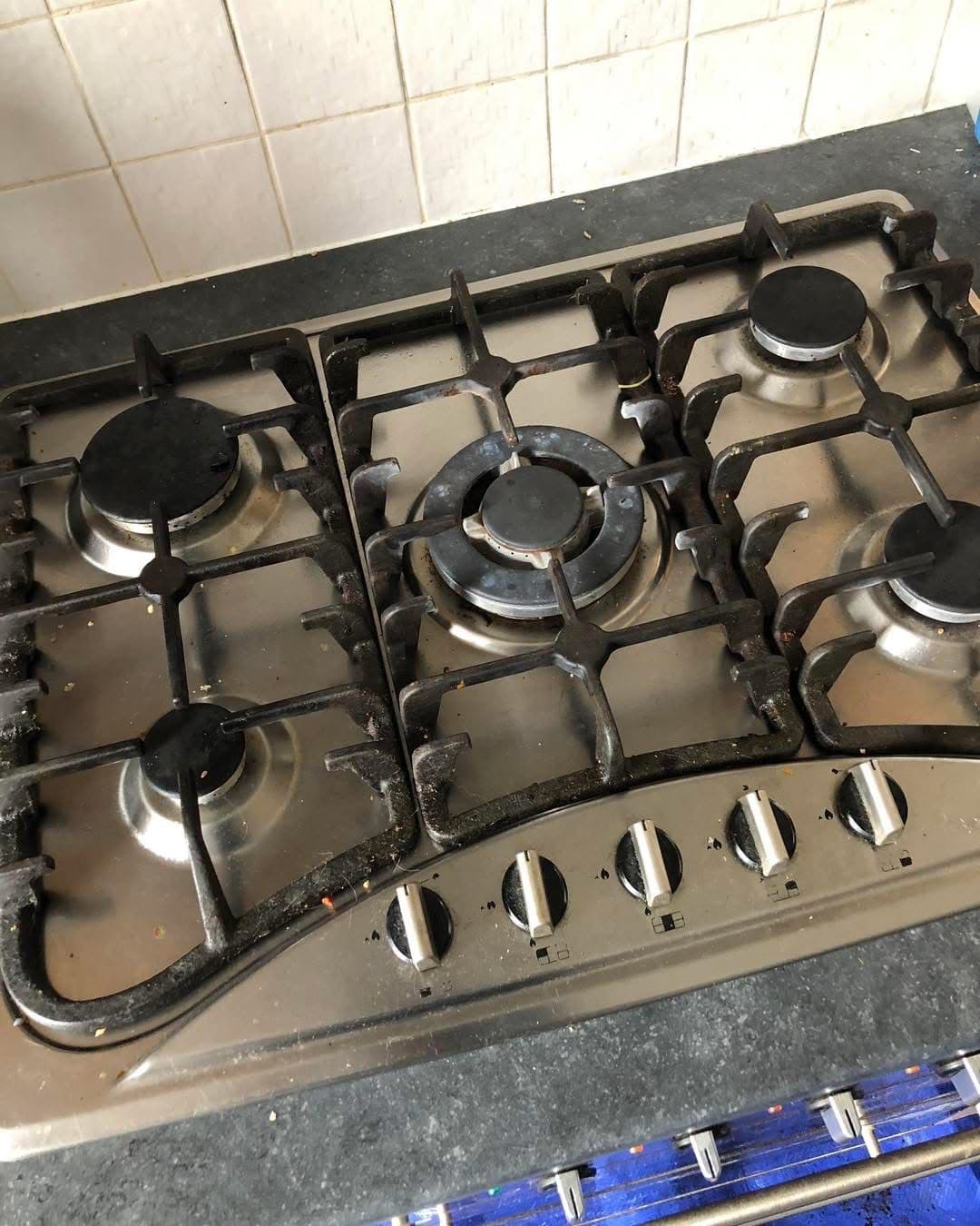 Dirty 5-burner gas hob with grease build-up before cleaning